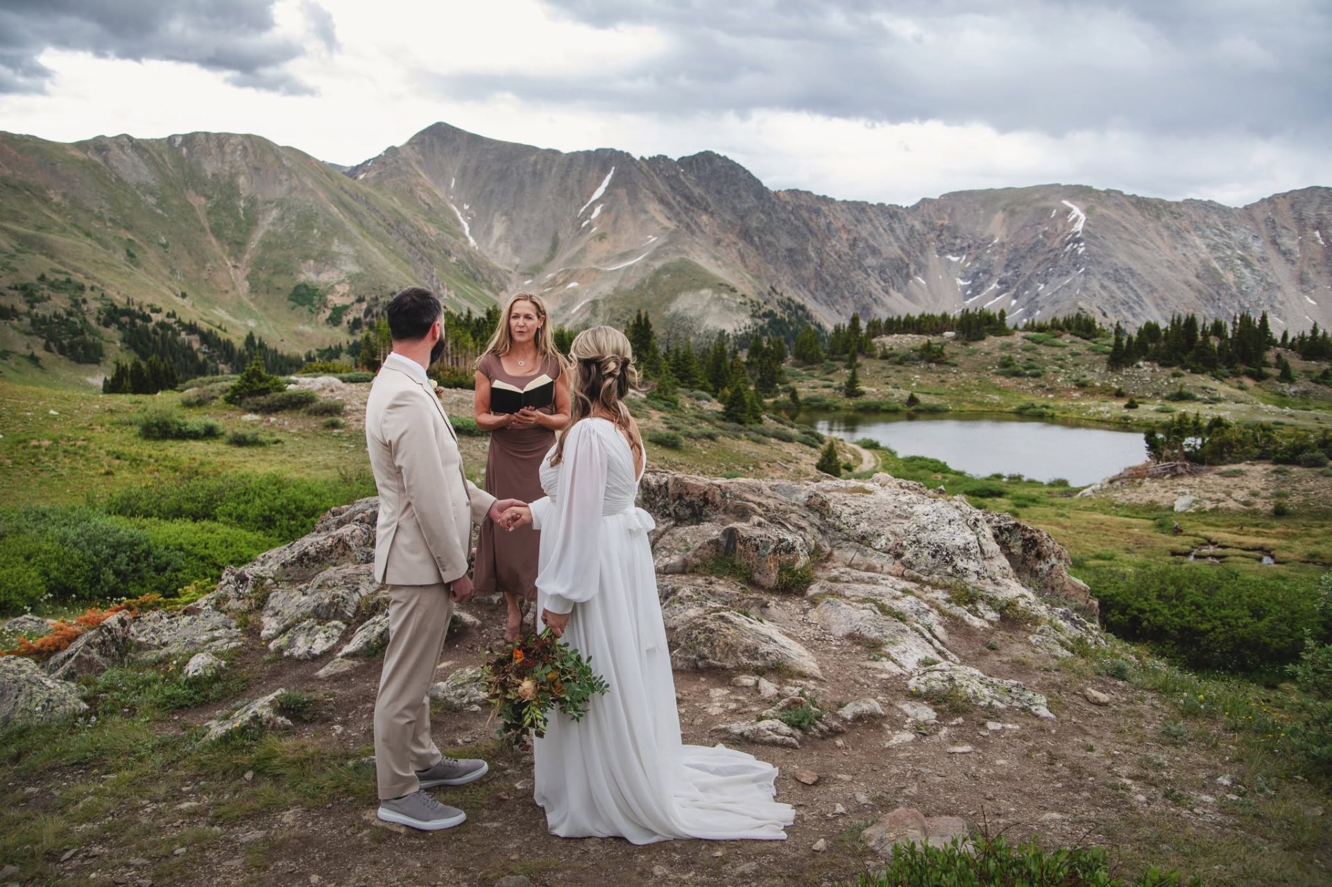 Wendee officiating a Colorado wedding on a mountain ridge with a lake behind